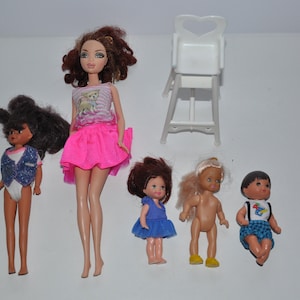 May include: A set of six dolls, including a tall doll with long brown hair wearing a pink skirt and a striped top, a smaller doll with brown hair wearing a blue vest and a white swimsuit, a doll with brown hair wearing a blue dress, a doll with blonde hair wearing no clothes, a doll with brown hair wearing a blue and white shirt and blue and white shorts, and a white plastic high chair.