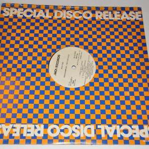 May include: A white vinyl record with a black and white checkered label. The label has the text "MCA Records" and "Special Disco Release" printed on it. The record is on a blue and orange checkered background.
