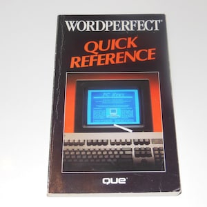 May include: A vintage "WordPerfect Quick Reference" book. The cover is black with orange text and a graphic of a computer screen displaying "PC News." The book is published by "que."