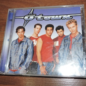 May include: A CD case with a blue background and a white star. The band "O-Town" is printed in white letters. Five young men are pictured on the front of the case.