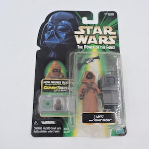 Könnte beinhalten: Star Wars "The Power of the Force" Actionfiguren-Set mit einem Jawa und einem "Gonk" Droiden. Die Figuren befinden sich in einer transparenten Kunststoffhülle mit einer grün-schwarzen Star Wars-Rückseite. Der Text "Now Figures Talk!"