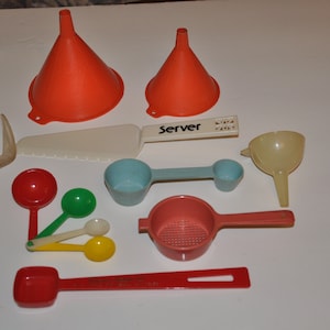 May include: A set of 10 kitchen utensils, including a fork, a spatula, a strainer, a funnel, and measuring spoons. The utensils are made of plastic and are in various colours, including red, blue, green, and yellow.