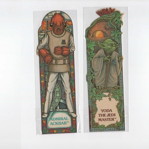 Op de afbeelding: Twee Star Wars-illustraties voor bladwijzers. De linker bladwijzer toont admiraal Ackbar, een Mon Calamari, in een wit uniform met een rode en oranje achtergrond. De rechter bladwijzer toont Yoda, een Jedi-meester, in een groene mantel met een groene en bruine achtergrond. De tekst op de linker bladwijzer luidt "ADMIRAL ACKBAR". De tekst op de rechter bladwijzer luidt "YODA THE JEDI MASTER".