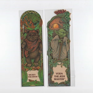 May include: Two Star Wars themed bookmarks. The bookmark on the left features Wicket the Ewok with a spear. The bookmark on the right features Yoda with a walking stick. Both bookmarks have a green, brown, and orange colour scheme.