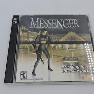May include: A CD-ROM case for the video game "The Messenger." The cover art features a woman in a black outfit holding a weapon, with a cityscape and pyramid in the background. The text "Breaking in is the easy part..." is visible.