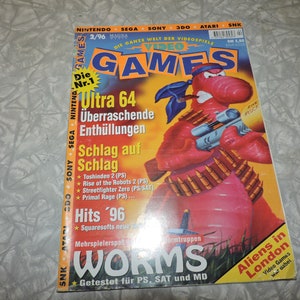 May include: A magazine cover featuring a red cartoon worm holding a gun. The magazine is titled "Video Games" and the issue number is 2/96. The cover also features the text "Ultra 64" and "Worms".