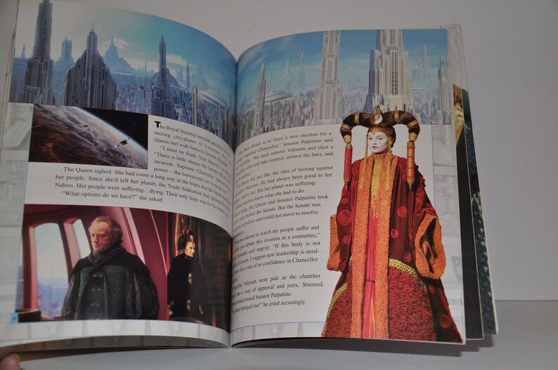 May include: An open book showing a page with a picture of a woman in a red and gold robe. The text on the page reads "The Queen sighed. She had come a long way in the battles to save her people. Since she left her planet, the Trade Federation had been destroying Naboo. Her people were suffering, dying. Their only hope was the Jedi. "What options do we have?" she asked."