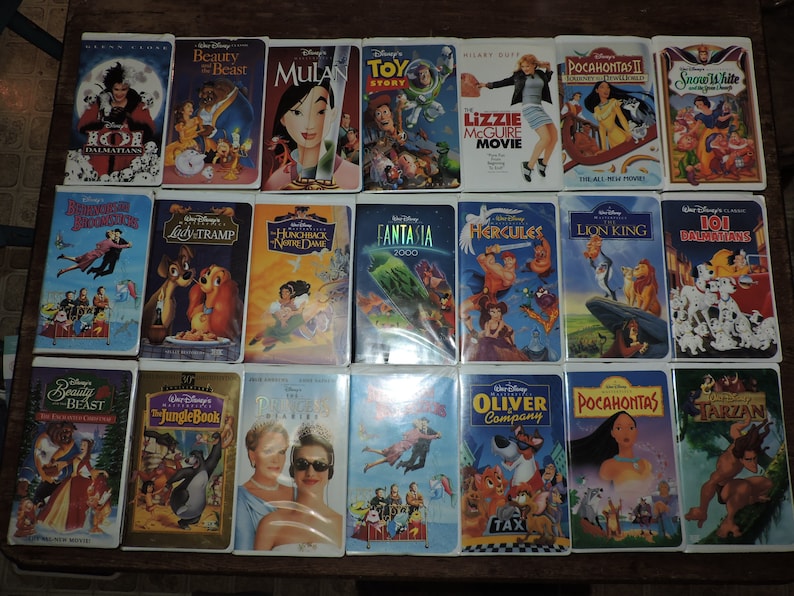 Pu&ograve; includere: Una collezione di videocassette VHS Disney, con titoli come "La Bella e la Bestia", "Mulan" e "Toy Story". Le videocassette presentano opere d'arte e titoli colorati, evocando la nostalgia dei classici film d'animazione.