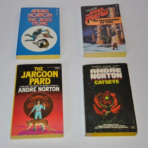 May include: Four paperback science fiction books by Andre Norton. The books are titled "The Zero Stone", "The Crossroads of Time", "The Jargon Pard", and "Catseye".