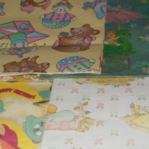 May include: A stack of colourful wrapping paper featuring various designs, including a clown, a teddy bear, a heart-shaped pinwheel, and a baby sleeping in a cot. The paper is ideal for wrapping gifts for birthdays or other special occasions.