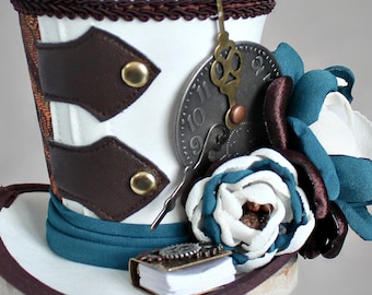 May include: White top hat with brown leather accents, a teal blue ribbon, and a clock face with a key attached. The hat is decorated with a white and teal blue flower.