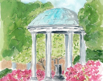 以下が含まれることがあります： 青い屋根と白い柱のあるガゼボが、緑豊かな木々とピンクの花に囲まれている。ガゼボは大学のキャンパスにある人気のランドマークです。