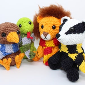 May include: Four handmade crochet stuffed animals: an owl, a snake, a lion, and a badger. Each animal wears a scarf in different colors. The owl is brown with a blue and white scarf. The snake is green with a green and gray scarf.