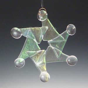 May include: A green iridescent glass star ornament with a gold wire hanger. The star is made of many small pieces of glass that are fused together.