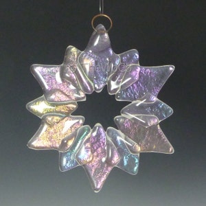 May include: A iridescent glass snowflake ornament with a starburst design. The ornament is clear with a rainbow sheen.