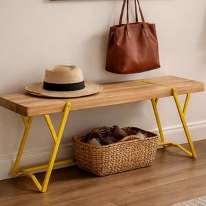 Könnte beinhalten: Zwei Holzbänke mit Metallbeinen, eine mit leuchtend gelben Beinen und die andere mit roten Beinen. Die Bänke sind rechteckig und haben eine natürliche Holzmaserung. Ein Strohhut und eine braune Ledertasche stehen auf der gelbbeinigen Bank.