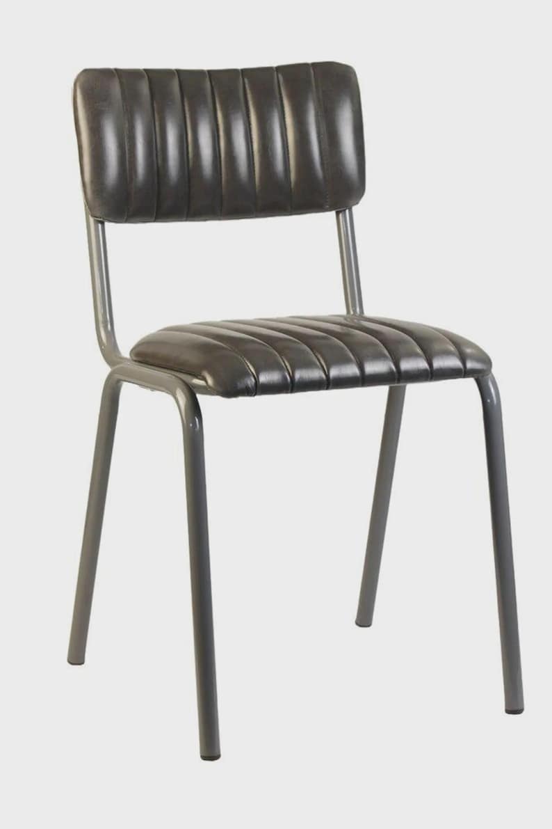May include: A grey metal chair with a padded seat and backrest. The seat and back have a ribbed design. The chair has four legs and a simple, industrial design. Suitable for dining or as an accent piece.