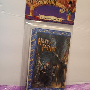 May include: A pack of six Harry Potter invitation cards in clear plastic packaging. The header features the Harry Potter logo and a character illustration. The cards depict a scene with characters in a stone hallway with a suit of armor and ghosts.