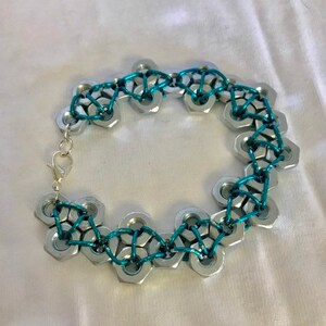 May include: A bracelet made of silver-toned metal nuts connected by turquoise wire.