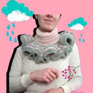 May include: A white sweater with a pink and gray ruffled collar. The sweater is worn by a person with a pink background. The background also has painted images of clouds, raindrops, flowers, and berries.