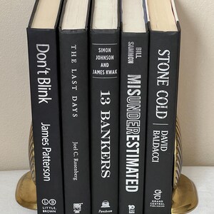 May include: A white ceramic mug with a black handle and the text "But First, Coffee" in a bold, black font. The mug is set against a blurred background, suggesting a cozy setting.