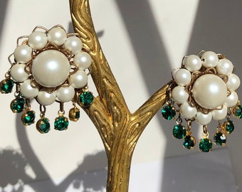 May include: A pair of gold tone earrings with a cluster of white pearls and dangling green crystals.
