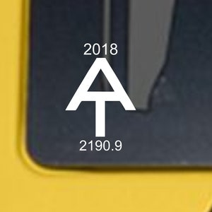 May include: A white sticker on a yellow car with the text "2018" above a white "A" with a white "T" inside, and the text "2190.9" below.