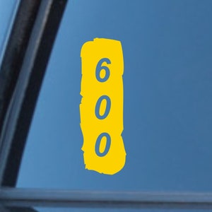 May include: Yellow sticker with the number 600 in blue on a car window.