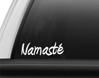 May include: White vinyl decal with the word "Namaste" in a cursive font, applied to the rear window of a black pickup truck.