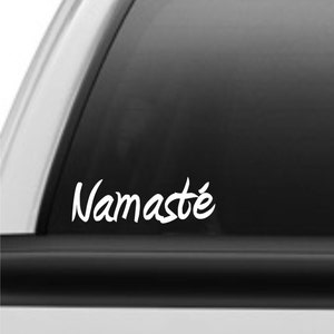 May include: White vinyl decal with the word "Namaste" in a cursive font, applied to the rear window of a black pickup truck.