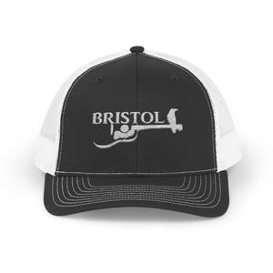May include: Black and white trucker hat with a white mesh back. The hat has an embroidered logo that says "BRISTOL" with a stylized image of a person in a boat.