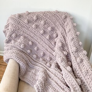 May include: A soft, plush, mauve-colored crochet throw blanket with a textured, bobble stitch pattern.
