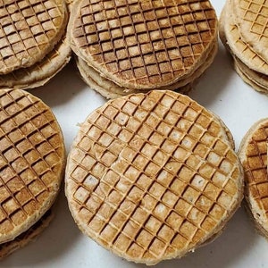 May include: Several stacks of round, golden-brown waffles with a distinctive grid pattern. The waffles appear freshly made, with a slightly toasted appearance. The image showcases a variety of waffle stacks, suggesting a batch of homemade treats.