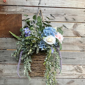 Large basket style door wreath loaded with greenery and flowers