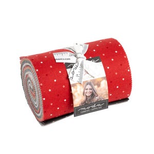 May include: A roll of red fabric with white polka dots. The fabric is rolled up and tied with a white ribbon. A tag with the text "moda fabrics - supplies" is attached to the roll.