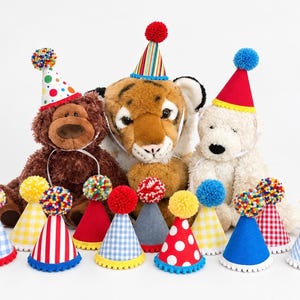 Pode incluir: Uma cole&ccedil;&atilde;o de pequenos chap&eacute;us de festa c&oacute;nicos em v&aacute;rias cores e padr&otilde;es, incluindo xadrez, riscas e bolinhas, cada um rematado com um pompom colorido. Tr&ecirc;s animais de peluche, um urso castanho, um tigre e um urso branco, usam chap&eacute;us semelhantes.