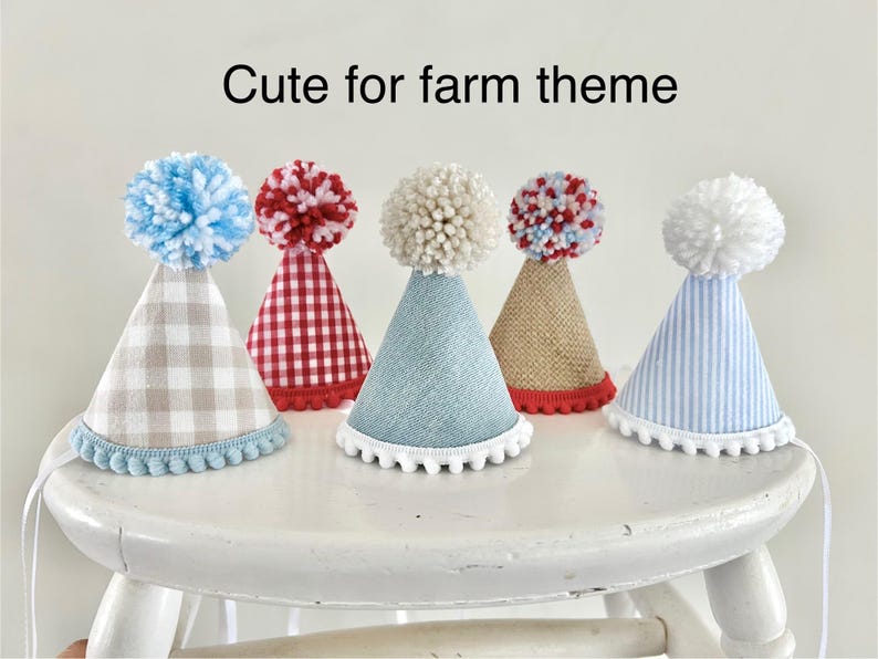 Pode incluir: Cinco chap&eacute;us de festa em formato de cone com pompons no topo e acabamento de pompons na base. Os chap&eacute;us apresentam v&aacute;rios padr&otilde;es, incluindo xadrez vichy bege, xadrez vichy vermelho, tecido azul texturizado, juta e listras azuis.