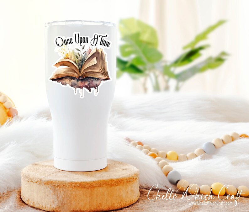 May include: White tumbler with a sticker of an open book with the text "Once Upon A Time" and watercolor-style flowers and leaves.