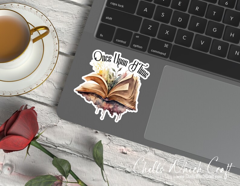 May include: A watercolor sticker featuring an open book with flowers and the text "Once Upon A Time". The sticker is on a laptop computer.