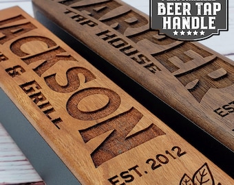 May include: Two wooden beer tap handles with personalized engravings. The top handle is dark brown with the text "Harper Tap House" and the bottom handle is light brown with the text "Jackson Bar & Grill Est. 2012".