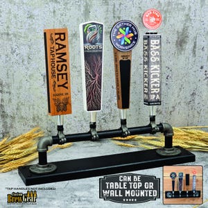 May include: A black, table-top or wall-mounted beer tap display with four tap handles. The tap handles have various logos and text, including "Ramsey Taphouse" and "Bass Kicker IPA." The display is made of black metal and has a rustic, industrial design.