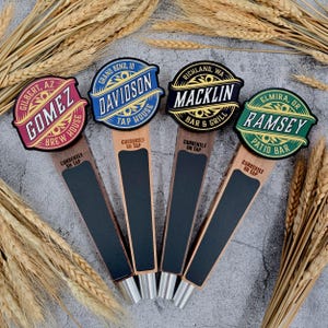 Peut inclure: Quatre poignées de bière en bois avec des enseignes circulaires portant les noms Gomez, Davidson, Macklin et Ramsey. Chaque poignée possède une section ardoise noire marquée Currently on Tap, des bases métalliques et du texte décoratif.