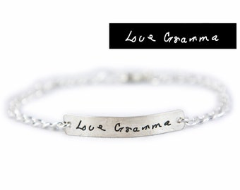 May include: Silver chain bracelet with a silver bar charm engraved with the handwritten message "Love Grandma".