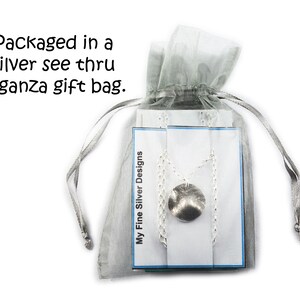 May include: A silver necklace with a textured, circular pendant is displayed inside a sheer, silver organza gift bag. The bag is tied with a matching ribbon. The text "My Fine Silver Designs" is visible on a card.