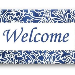 May include: A blue and white welcome sign with a paisley pattern. The sign says "Welcome" in a white font.