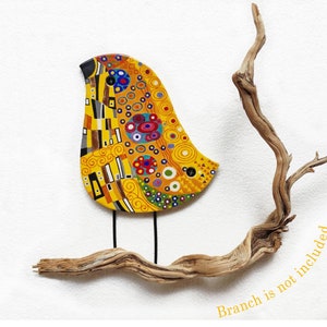 May include: A colorful, abstract bird sculpture with a yellow, orange, and blue design. The bird is perched on a branch, which is not included in the sale.