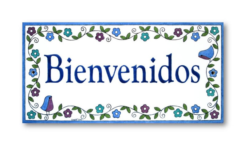 May include: A white ceramic sign with a blue border and floral design. The sign says "Bienvenidos" in blue lettering.