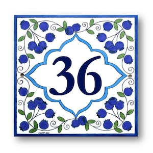 May include: A white ceramic tile with a blue and white border design. The tile features a blue floral pattern with blueberries and a white center with the number 36 in blue.