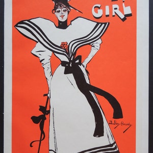 May include: A vintage poster advertising a musical called "A Gaiety Girl" featuring a woman in a white dress with black stripes and a large hat. The poster is on an orange background and has the text "A Gaiety Girl" and "Dudley Hardy" in black.