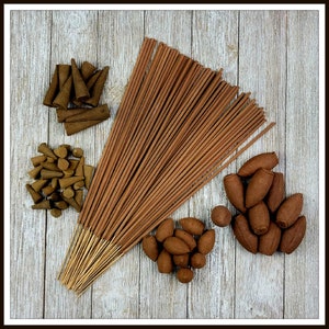 May include: A variety pack of incense featuring brown sticks, cones, and small brown incense pellets. The incense is arranged on a wooden surface.